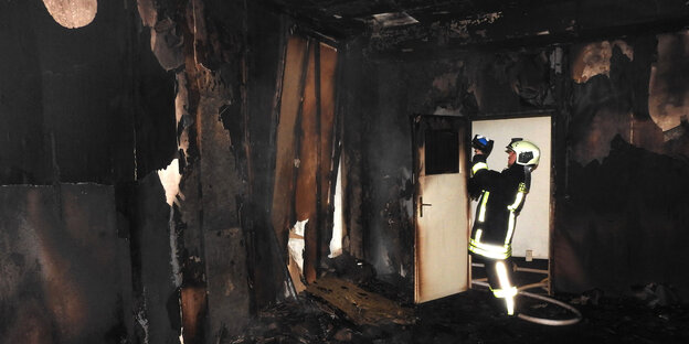 Ein Mitarbeiter der Feuerwehr begutachtet das ausgebrannte Gebäude Ein Mitarbeiter der Feuerwehr begutachtet das ausgebrannte Gebäude