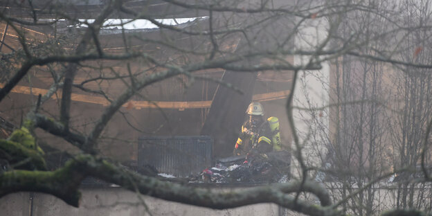 Ein Mitarbeiter der Feuerwehr begutachtet das verkohlte Dach einer Unterkunft Ein Mitarbeiter der Feuerwehr begutachtet das verkohlte Dach einer Unterkunft