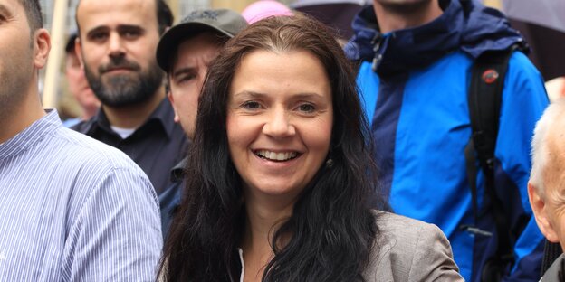 Frau mit langen dunklen Haaren auf einer Demonstration mit lauter Männern Frau mit langen dunklen Haaren auf einer Demonstration mit lauter Männern