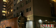 Ein Polizist steht abends vor einem Hochhaus
