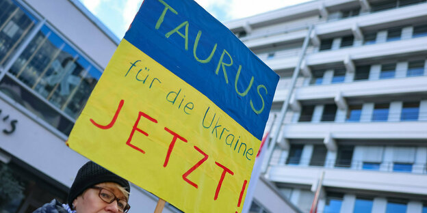 Eine Frau hält ein Blau-Gelbes Demo-Schild auf dem steht: Taurus für die Ukraine Jetzt!
