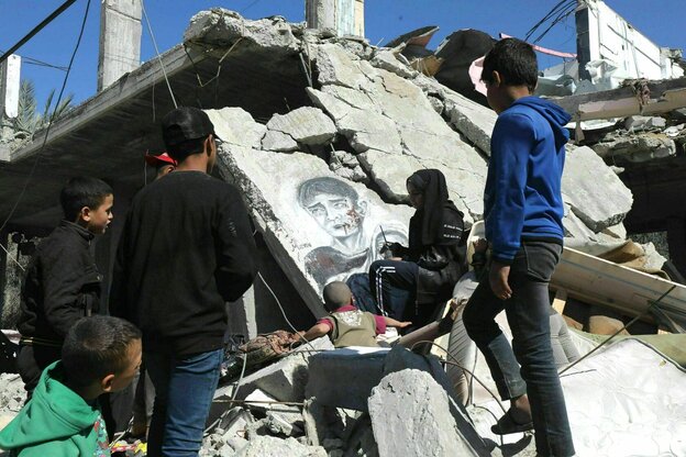 Menna Hamouda paints the portrait of a bleeding young man on the wall of a destroyed house.  She is surrounded by curious children.
