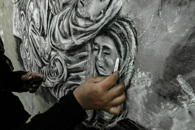 Close-up showing Menna Hamouda working on a painting with chalk.
