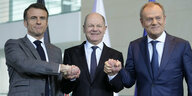 Präsident Macron, Bundeskanzler Scholz und Premierminister Tusk halten sich an den Händen.