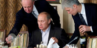 Prigoschin steht hinter Putin, der am Tisch sitzt und isst