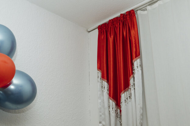 A red and white curtain with tassels and blue and red balloons.