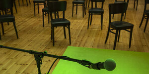 grünes Licht liegt auf einem Tisch, darüber ein Mikrofon, im Hintergrund Stühle
