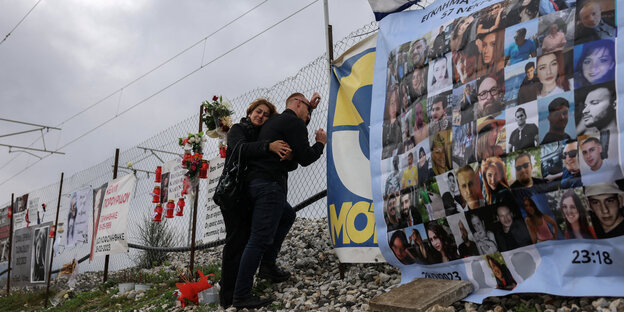 A couple remembers the victims of the train accident on the fence of the accident site
