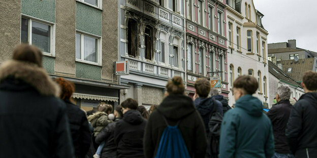 People in front of a house with traces of fire on the windows
