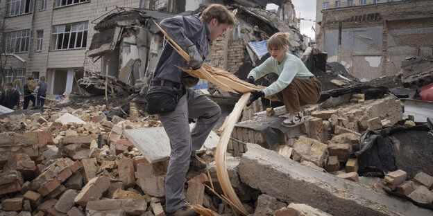 People stand on the rubble and remove pieces