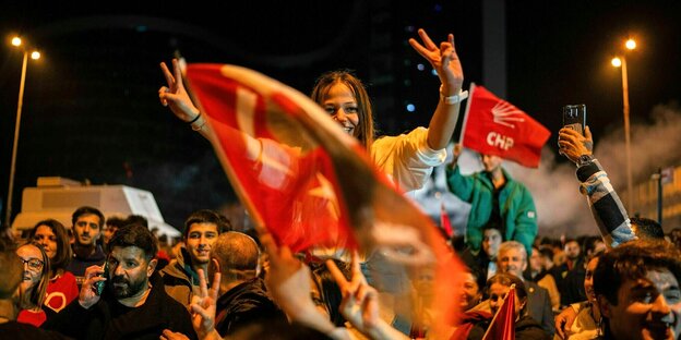 A woman celebrates the CHP's election victory in Ankara on the shoulders of another celebrant, showing the victory sign with both hands.