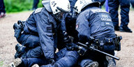 Zwei Polizisten knien auf einem Mann, von dem man nur die Beine sieht