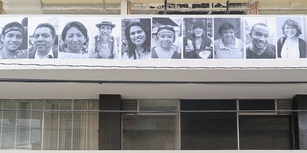 Ein Haus mit Schwarzweißfotos von Gesichtern an einem Balkon. Ein Haus mit Schwarzweißfotos von Gesichtern an einem Balkon.