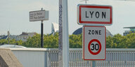 Ein Verkehrsschild für Tempo 30 unter dem Ortseingangsschild von Lyon