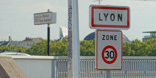 Ein Verkehrsschild für Tempo 30 unter dem Ortseingangsschild von Lyon