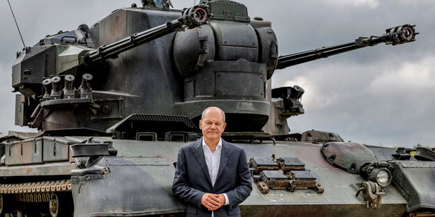 Bundeskanzler Olaf Scholz steht vor einem Panzer