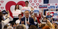 Donald Tusk, polnischer Premier vor einer Wand mit Herzen und Wahlkampfplakaten
