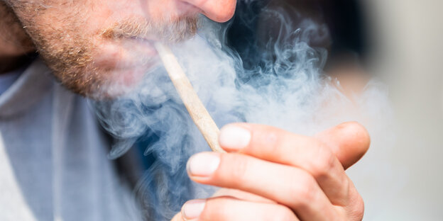 Das Bild zeigt einen Joint rauchenden Mann