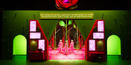 Blick auf die Bühne der Inszenierung "Die Möglichkeit des Bösen", mit einer Toranordnung in Grün und Rot, eine große Rose darüber