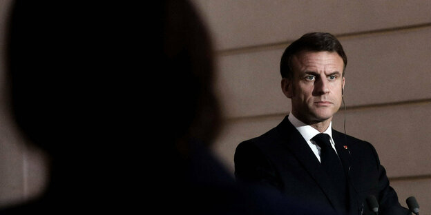 Emmanuel Macron, französischer Präsident, im schwarzen Anzug schaut ernst.