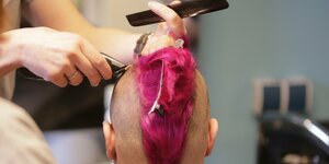 ein Punk sitzt beim Friseur