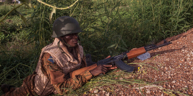 Ein Soldat aus Burkina Faso liegt in Tarnkleidung auf dem Boden. Ein Soldat aus Burkina Faso liegt in Tarnkleidung auf dem Boden.