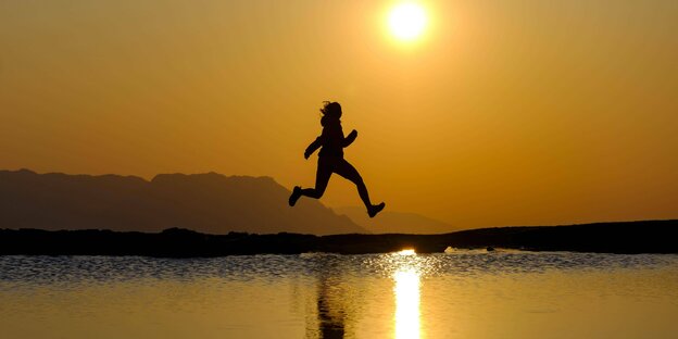 A person jumps in front of the sunset.