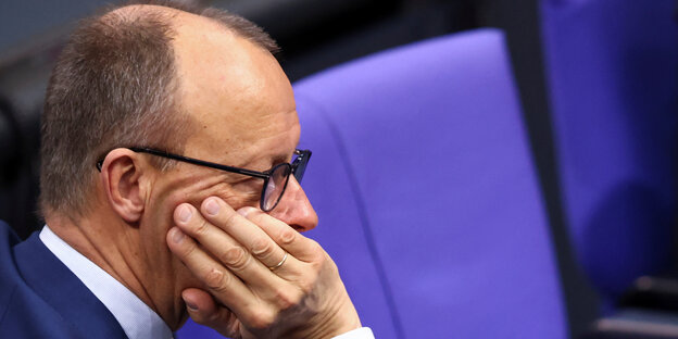 Friedrich Merz sits in the Bundestag and rests his chin on his hand