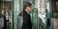 Maximilian Krah geht schlecht gelaunt durch die Drehtür im Bundestag