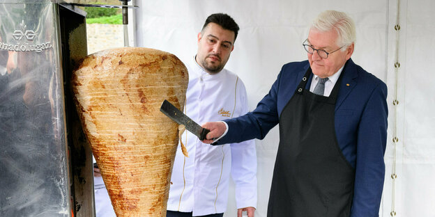 Federal President Steinmeier stands in front of a kebab skewer and cuts it