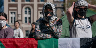 Demonstrierende im Freien mit Palästinaflaggen, Masken und Kufiyas