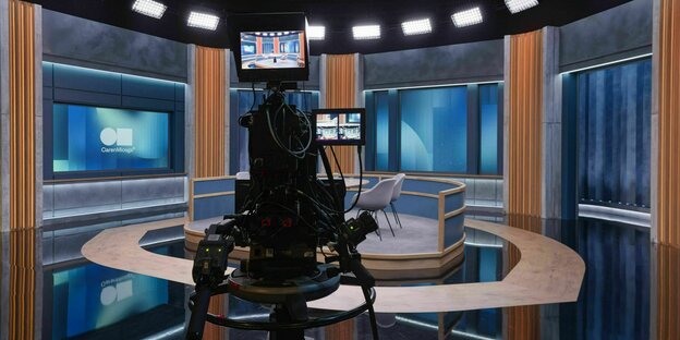 Ein Fernsehstudio mit einer großen Kamera, die vor Stühlen in der Mitte des Raumes, steht