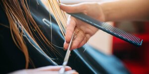 Bei einem Frisörbesuch werden einer Person die Haare geschnitten.