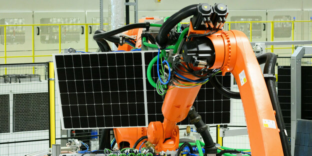Roboterarm einer Maschine hält ein Solarmodul