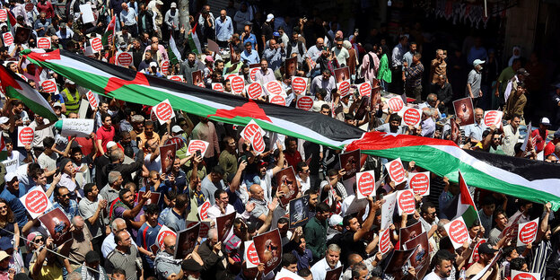 Protesters carry flags and banners during a demonstration in support of Palestinians in the Gaza Strip amid the ongoing conflict between Israel and the Palestinian Islamist group Hamas in Amman, Jordan, on May 3, 2024.