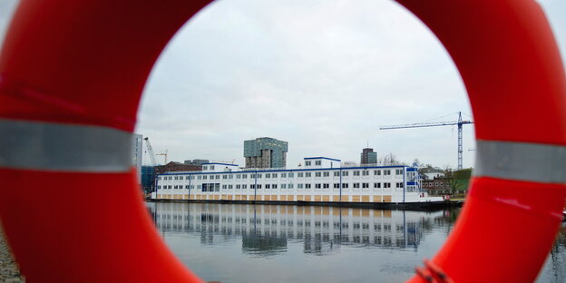 Durch einen Rettungsring ist eine Wohnschiff für Geflüchtete zu sehen Durch einen Rettungsring ist eine Wohnschiff für Geflüchtete zu sehen