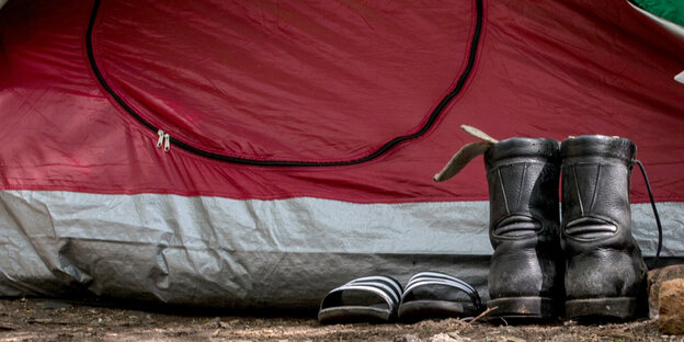 Schmutzige Stiefel und Badelatschen vor einem Zelt Schmutzige Stiefel und Badelatschen vor einem Zelt