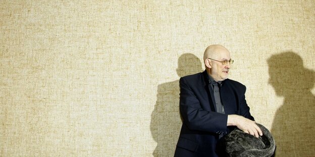 Mann mit kahlem Schädel und Brille vor Wand Mann mit kahlem Schädel und Brille vor Wand