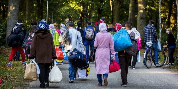 Eine Gruppe von Menschen ist von hinten auf einer Straße laufend zu sehen Eine Gruppe von Menschen ist von hinten auf einer Straße laufend zu sehen