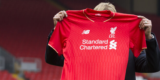 Ein Mann hält ein rotes Trikot hoch. Ein Mann hält ein rotes Trikot hoch.
