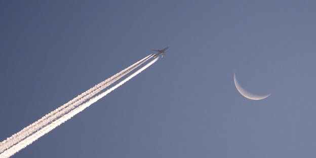Ein Flugzeug fliegt am Morgenhimmel vor dem Mond vorbei. Ein Flugzeug fliegt am Morgenhimmel vor dem Mond vorbei.