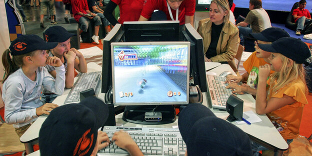 Eine Gruppe Kinder starrt gebannt auf Bildschirme und spielt Computerspiele. Eine Gruppe Kinder starrt gebannt auf Bildschirme und spielt Computerspiele.