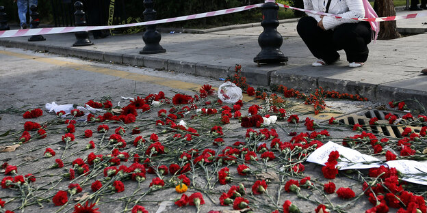 Eine Frau hockt neben niedergelegten Blumen für die Opfer in Ankara. Eine Frau hockt neben niedergelegten Blumen für die Opfer in Ankara.