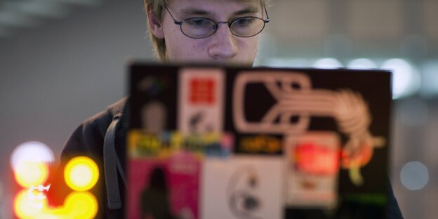 Ein Nerd sitzt vor einem beklebten Laptop Ein Nerd sitzt vor einem beklebten Laptop