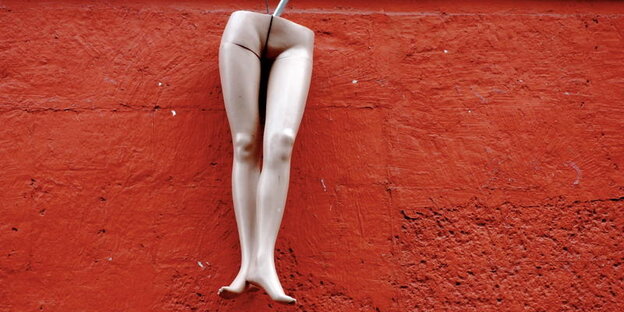 Beine einer Schaufensterpuppe vor roter Wand Beine einer Schaufensterpuppe vor roter Wand