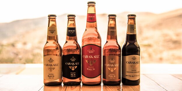Fünf Bierflaschen der Carakale stehen vor einem steinigen Hintergurnd Fünf Bierflaschen der Carakale stehen vor einem steinigen Hintergurnd