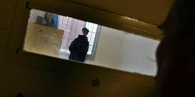 Ein junger Mann steht in einer Gefängniszelle Ein junger Mann steht in einer Gefängniszelle