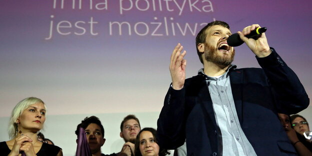 Adrian Zandberg spricht auf einer Parteiveranstaltung in ein Mikro. Adrian Zandberg spricht auf einer Parteiveranstaltung in ein Mikro.