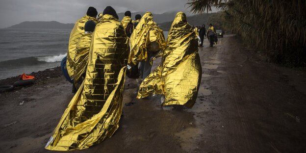 Flüchtlinge auf der griechischen Insel Lesbos. Isolierdecken sollen vor Wind und Wetter etwas Schutz bieten. Flüchtlinge auf der griechischen Insel Lesbos. Isolierdecken sollen vor Wind und Wetter etwas Schutz bieten.