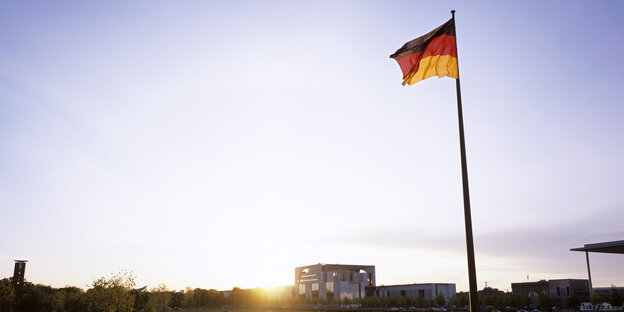 Deutschland-Flagge mit Teilen des Kanzleramts im Hintergrund. Deutschland-Flagge mit Teilen des Kanzleramts im Hintergrund.
